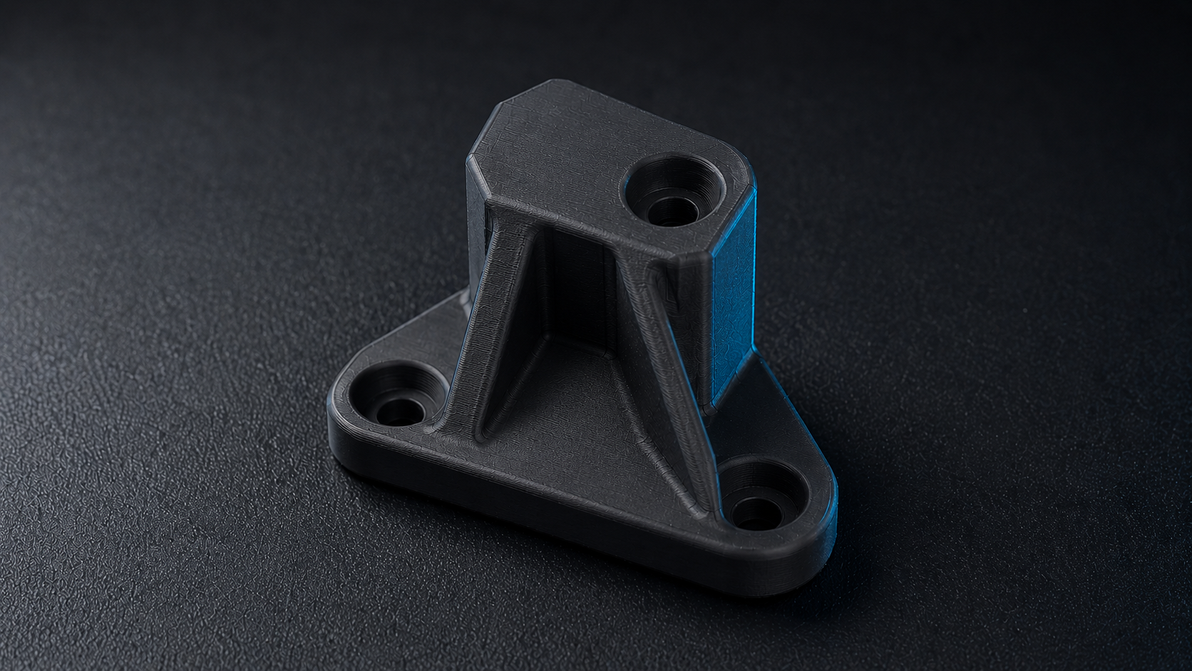 Finished FDM-printed carbon-fibre mechanical bracket on the studio bench
